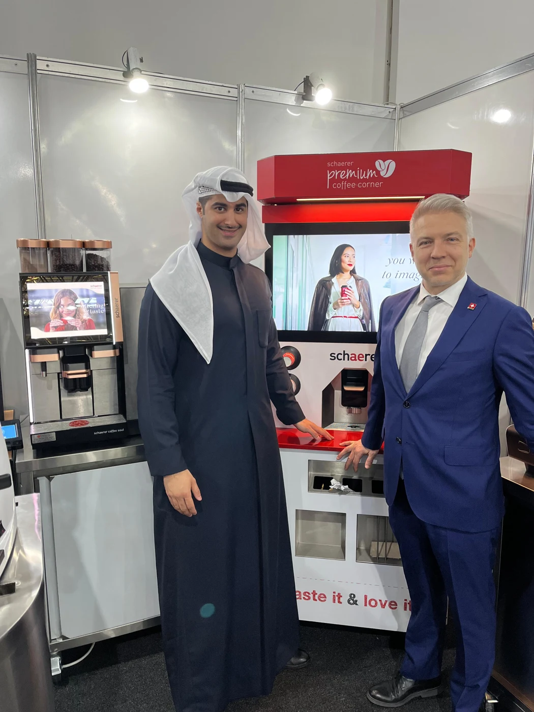 Two business representatives beside professional coffee machines at an exhibition